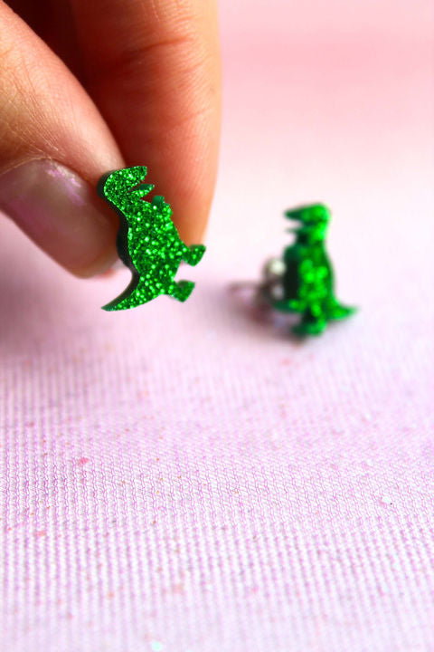 Glimmer dino ørestikker i plexiglas