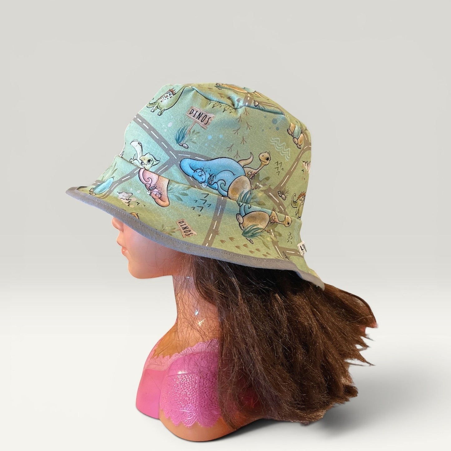 Håndlavet af reversible green jersey bucket hat for kids with dinosaur print and grey trim. Size 50 (6-12 months).
