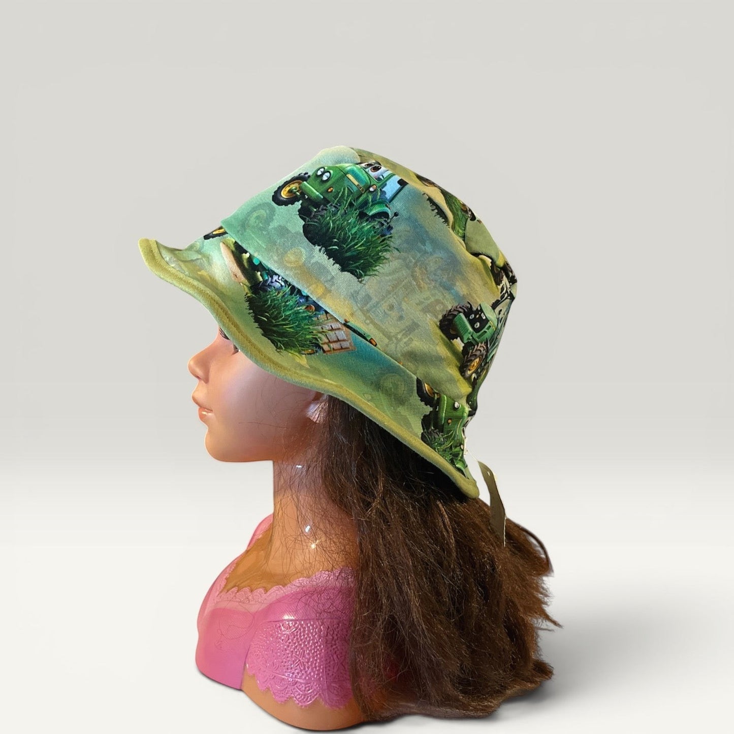 Håndlavet af reversible bucket hat for children, size 50, with a green tractor print on one side and solid green on the other. Made of jersey.