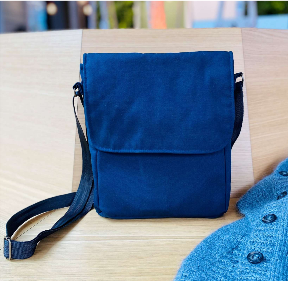 Eksempel på en færdig blå StockholmerTaske med klap, forlomme og sort justerbar rem. Produktet er en PDF-syvejledning og mønster, ikke en færdig taske.