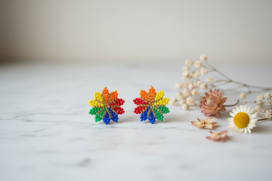 Stylet produktfoto af håndlavede miyuki øreringe formet som regnbue blomst – perfekt til Pride