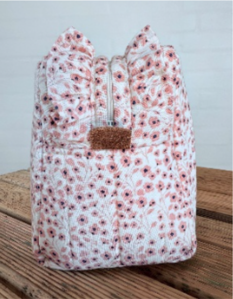 FlæseToiletTaske med rosa blomstermønster set fra enden med flæser og lædersnip ved lynlåsen. Eksempel på en færdig taske, produktet er en PDF-syvejledning.